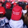 Supporters wearing MAGA hats listen