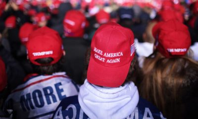 Supporters wearing MAGA hats listen
